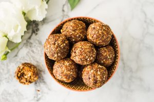 Sugar-free almond butter energy balls with flaxseed and chia seeds in a bowl on a marble counter