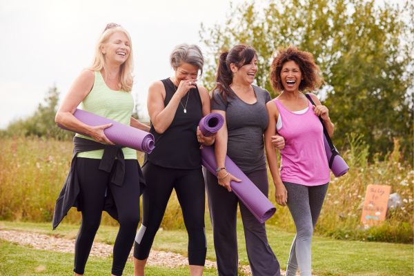 Group of midlife women walking outdoors with yoga mats, representing movement and hormone balance in midlife.
