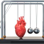A red anatomical heart suspended inside a Newton’s cradle, replacing the center ball to symbolize heart rhythm and balance.