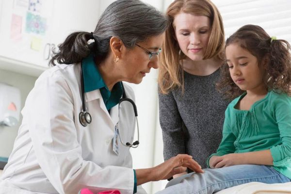 Pediatrician examining a child with her mother during an evaluation for symptoms that may be related to Vitamin C deficiency and modern scurvy.