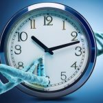 A turquoise DNA double helix curves around an analog clock against a blue background, illustrating biological aging.