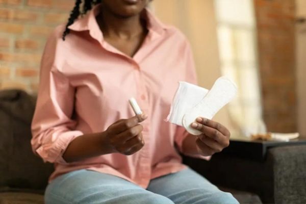 Woman holding menstrual products while managing heavy periods and menstrual health.